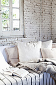 Sofa with cushions in room with a whitewashed brick wall