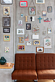 Pictures, photos and decorative letters on concrete wall with brown armchairs below