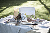 Linen tablecloth, place setting and candle on an Easter table in the garden