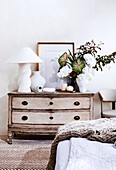 Antique chest of drawers with table lamp, vases and bouquet of flowers