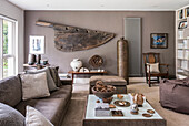The rudder of an old spanish Galleon hangs on the wall of a living room, tall wicker vase, sofa and coffee table