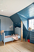 Toddler bed under the eaves in a blue children's bedroom