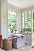 Wooden chest and basket in summery conservatory with lattice windows