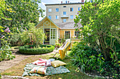 Blanket and cushions in sunny garden outside yellow Swedish house