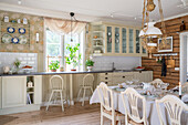 Wohnküche mit cremefarbener Küchenzeile, im Vordergrund gedeckter Esstisch