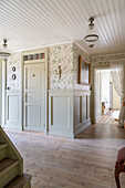 Spacious hallway with wooden panelling and vintage-style wallpaper