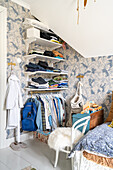 Open wardrobe in boy's bedroom with blue-white wallpaper