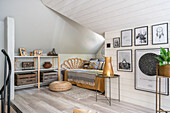 Cosy chaise longue, shelf and pictures on the wall in bright attic bedroom