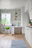 Bright country kitchen with patterned wallpaper and wooden floorboards