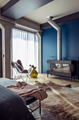 Wood-burning stove against dark blue wall in bedroom with fur rug