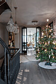 Illuminated Christmas tree on elegant landing with staircase