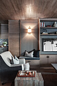 Beistelltisch, Sessel und maßgefertigtes Regal in elegantem Zimmer mit Holzverkleidung
