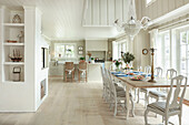 Dining table and Gustavian chairs in open-plan interior decorated in white