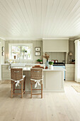 Wicker chairs at island counter in open-plan kitchen-dining room in Long Island style