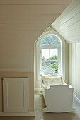 Baby's crib in window bay of arched window in room with beige wall panelling
