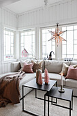 Coffee table, light grey sofa set with scatter cushions and Christmas decorations in window in living room