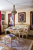 Antique ambiance with upholstered bench and chairs and paintings on walls