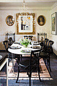 Table and black chairs in front of pictures in gilt frames on dining room walls