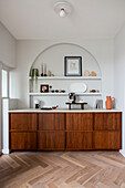 Fitted sideboard below shelves in arched niche