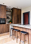 Barhocker an Kücheninsel mit Natursteinplatte, Schränke mit Holzfronten
