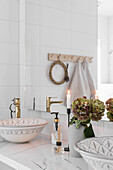 Waschtisch mit zwei Waschschüsseln, Blume und Kerze, darüber großer Wandspiegel