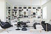 White living room with wall of shelves, sofa set, black table set, armchair and swing