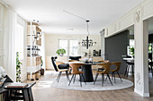 Dining area with round table and designer chairs, wine rack in the background