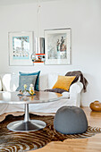 White sofa with scatter cushions and round table with pouffe on zebra skin rug in living room