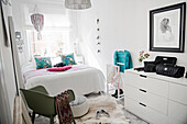 White dresser, valet stand and double bed in bright bedroom