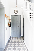 White hallway with staircase and blue-grey wooden door