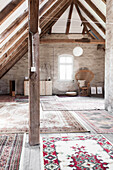 Offener Wohnraum mit vielen Teppichen, Sichtmauerwerk und Dachkonstruktion aus Holz