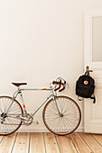 Bicycle next to open door with backpack in period apartment