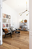 Blick ins Wohnzimmer mit schwarzen Stühlen, Beistelltisch und Bildergalerie an der Wand