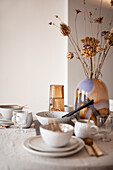 Set table with linen blanket, ceramic tableware, glass vase and dried grasses