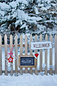 Welcome signs on the wooden fence in the snowy garden