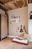 Play area, guitar collection, wall shelf and cupboard in children's room with high wooden ceiling