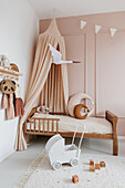 Girl's bedroom with wooden bed and canopy in nude shades