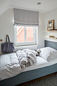Bed next to window with blind in child's room decorated in grey and white