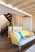 Sofa in front of wooden room divider to hallway and staircase
