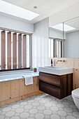 Badewanne mit Holzverkleidung vorm Fenster mit Holzlamellen