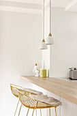 Two pendant lights above breakfast bar with wooden worktop and bar stools
