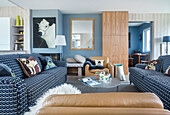 Open plan living room with blue and white covered sofas and light brown leather armchairs