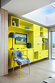 Grün-gelbe Wohnwand und Stuhl mit Tierfell in offenem Wohnraum mit Oberlicht