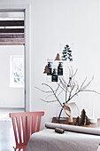 Roter Stuhl und Holztisch, rustikale Weihnachtsdekoration an der Wand und auf dem Tisch