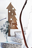 Cardboard Christmas tree with white paper baubles on wall next to staircase