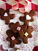 Gingerbread men with icing and cookie cutters on a red and white tablecloth