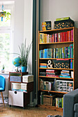 Full bookshelves next to boxes, globe and plant on top of rolling container in living room