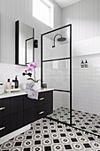 Bathroom vanity next to a shower area in bathroom with black and white patterned floor tiles