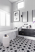 Bathroom vanity with an integrated sink next to bathtub in bathroom with black and white patterned floor tiles