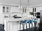 Kücheninsel mit Arbeitsplatte aus Carraramarmor und Barhocker mit blau-weißer Polsterung